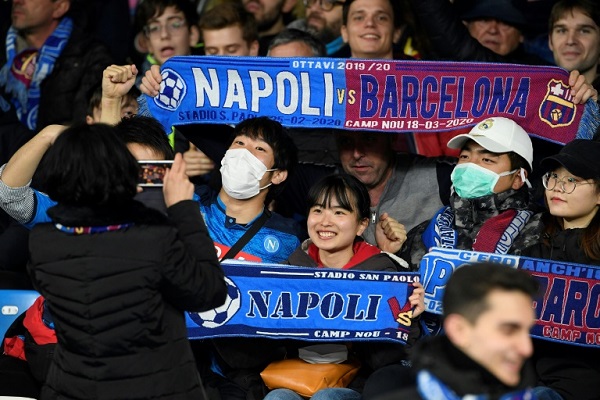 مشجعون يرتدون أقنعة واقية خلال حضورهم مباراة برشلونة ونابولي