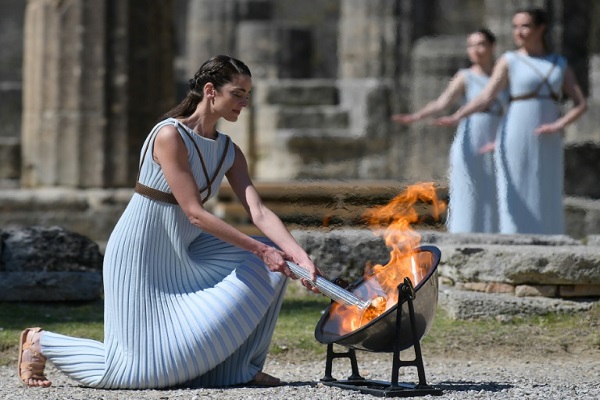 امرأة ترتدي الزي التقليدي لقسيسة تضيء الشعلة الاولمبية في اولمبيا في اليونان في 12 آذار/مارس 2020.