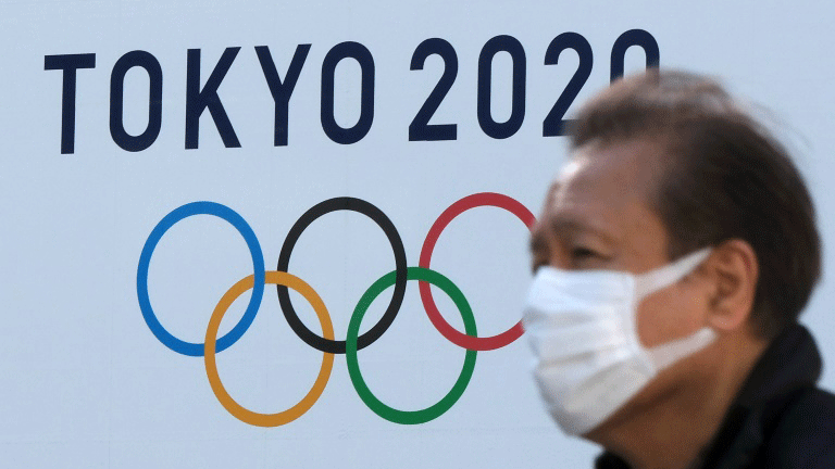 رجل يرتدي كمامة امام شعار اولمبياد طوكيو في 4 شباط/فبراير 2021