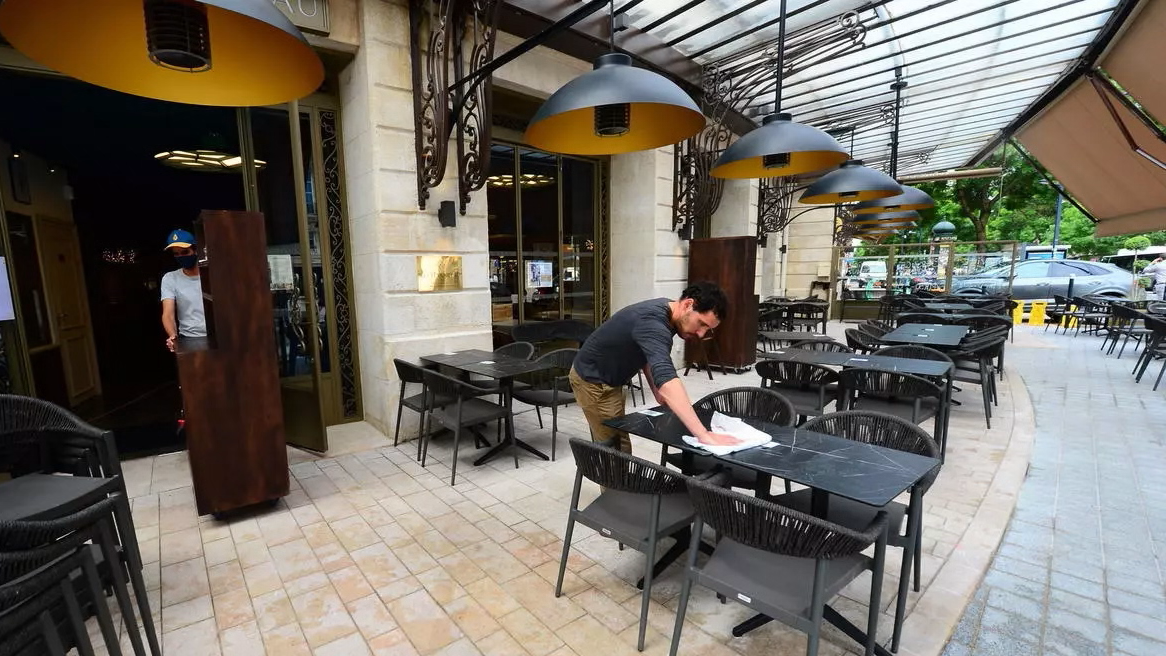 عامل ينظف طاولات استعداداً لإعادة فتح الباحات الخارجية للمطاعم في مطعم في مدينة بوردو في فرنسا