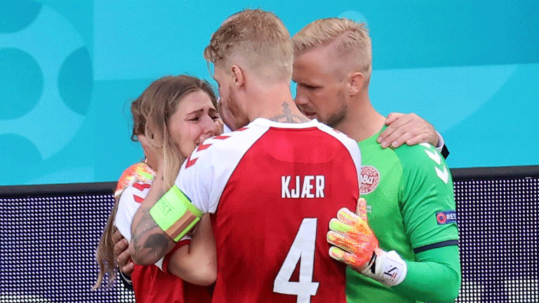 قائد منتخب الدنمارك سايمون كاير (رقم 4) محاولا مواساة صديقة زميله كريستيان اريكسن الذي سقط مغميا عليه خلال المباراة ضد فنلندا في كأس اوروبا. 12 حزيران/يونيو 2021