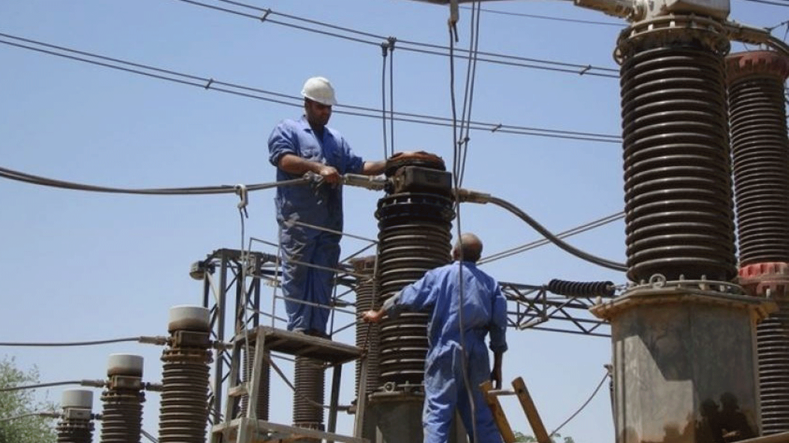 فنيون عراقيون يعملون على إعادة خطوط نقل الطاقة إلى العمل