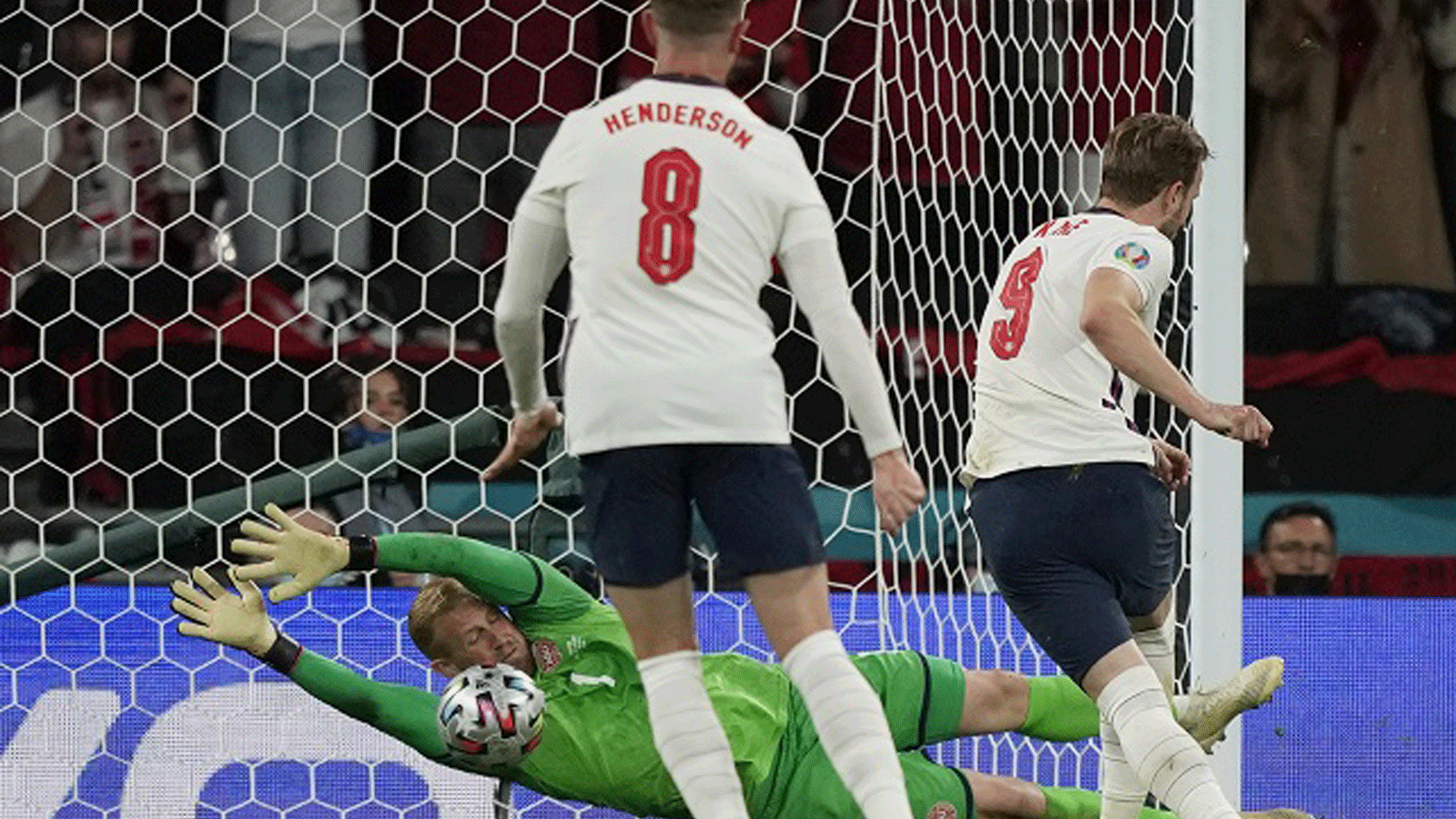 مهاجم إنجلترا هاري كين (يمين) يسدد ركلة جزاء في مرمى حارس الدنمارك كاسبر شميشيل (في الخلف) خلال مباراة نصف نهائي كأس الأمم الأوروبية لكرة القدم 2020 بين إنجلترا والدنمارك في ملعب ويمبلي بلندن في 7 تموز/يوليو 2021