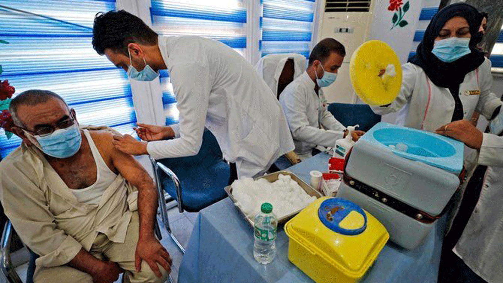 مسعفون عراقيون يقدمون لقاح Pfizer-BioNTech COVID-19 للأشخاص في مركز التطعيم في بغداد. تموز 2021 