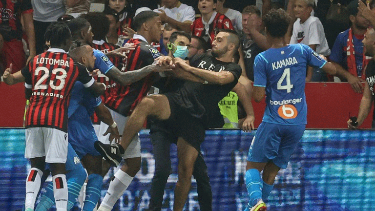 لاعبون من نيس ومرسيليا يحاولون إيقاف مشجع من دخول أرض ملعب أليانز ريفييرا في نيس، جنوب فرنسا، في 22 آب/أغسطس 2022