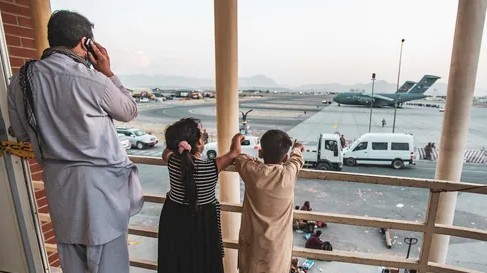 أفغاني وطفلاه ينتظرون دورهم في الإجلاء للسفر من مطار كابول 