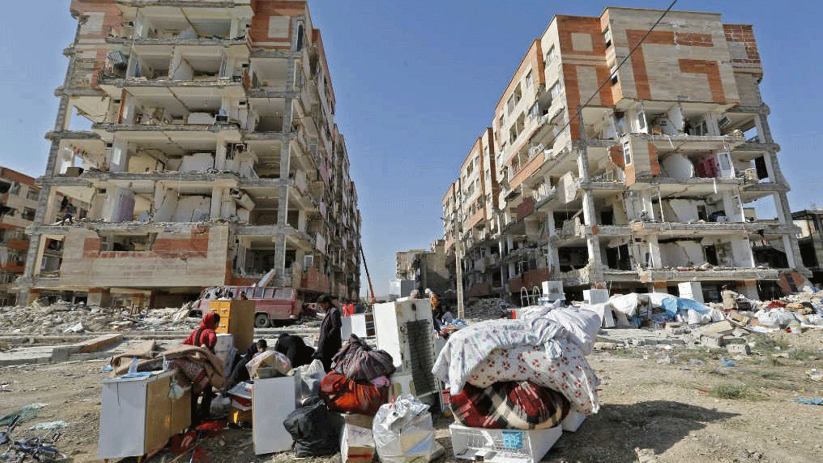 إيرانيون يجلسون خارج منازل متضررة بعد انتشال الأثاث والأجهزة المنزلية في بلدة ساربول زهاب في محافظة كرمانشاه غربي إيران. (15 نوفمبر 2017)