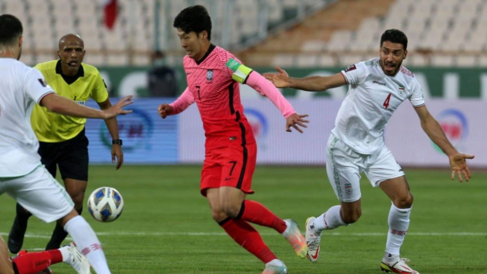 مهاجم كوريا الجنوبية سون هيونغ-مين (في الوسط) يسيطر على الكرة خلال لقاء فريقه أمام إيران ضمن منافسات المجموعة الأولى من التصفيات الآسيوية المؤهلة لمونديال قطر 2022 على ستاد آزادي في طهران. في 12 تشرين الأوّل/أكتوبر 2021.