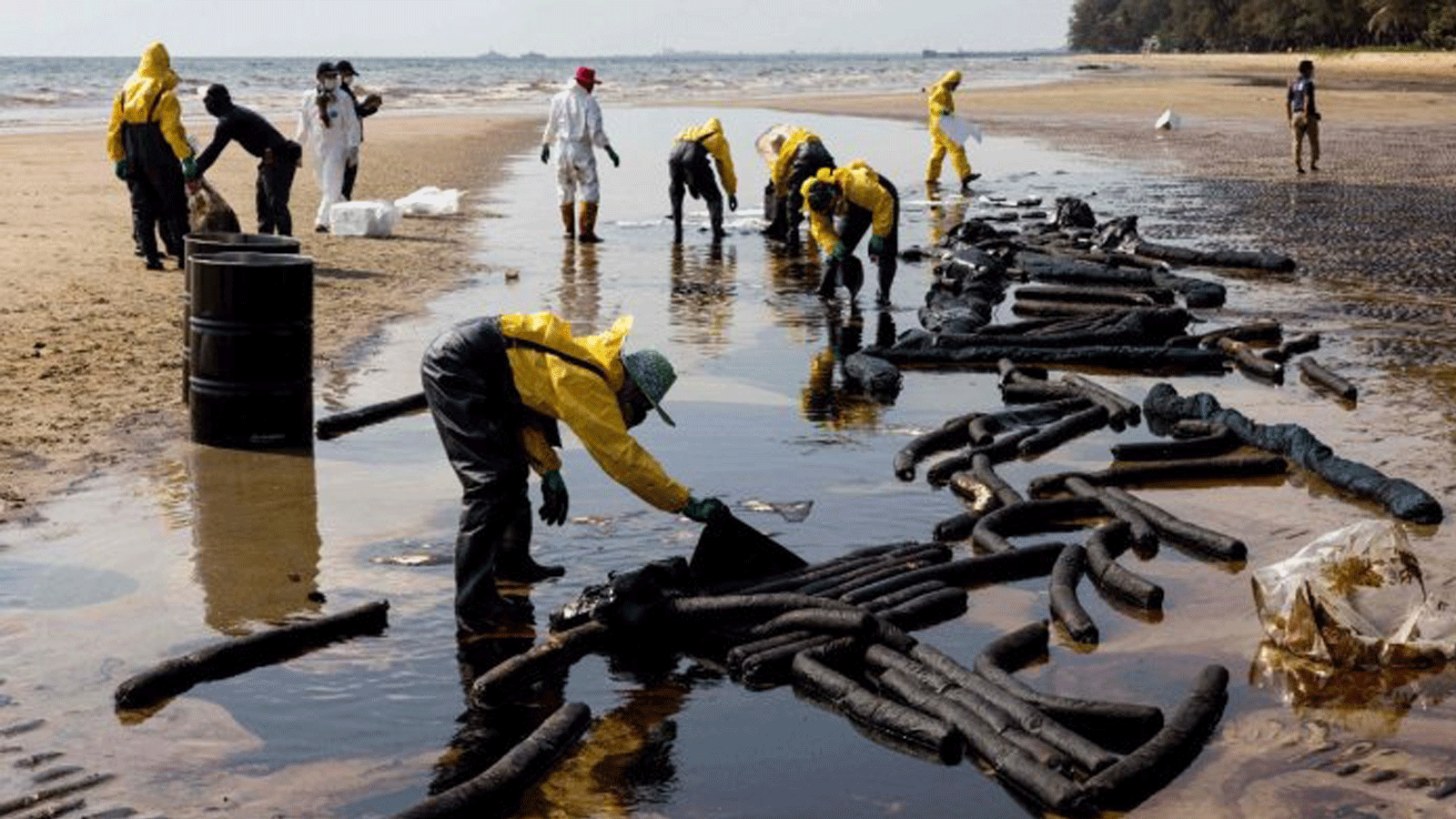 عمال ينظفون النفط الخام على شاطئ ماي رام فوينج في أعقاب تسرب ناجم عن تسرب في خط أنابيب تحت البحر مملوك لشركة Star Petroleum Refining Public Company Limited (SPRC) في Rayong. 