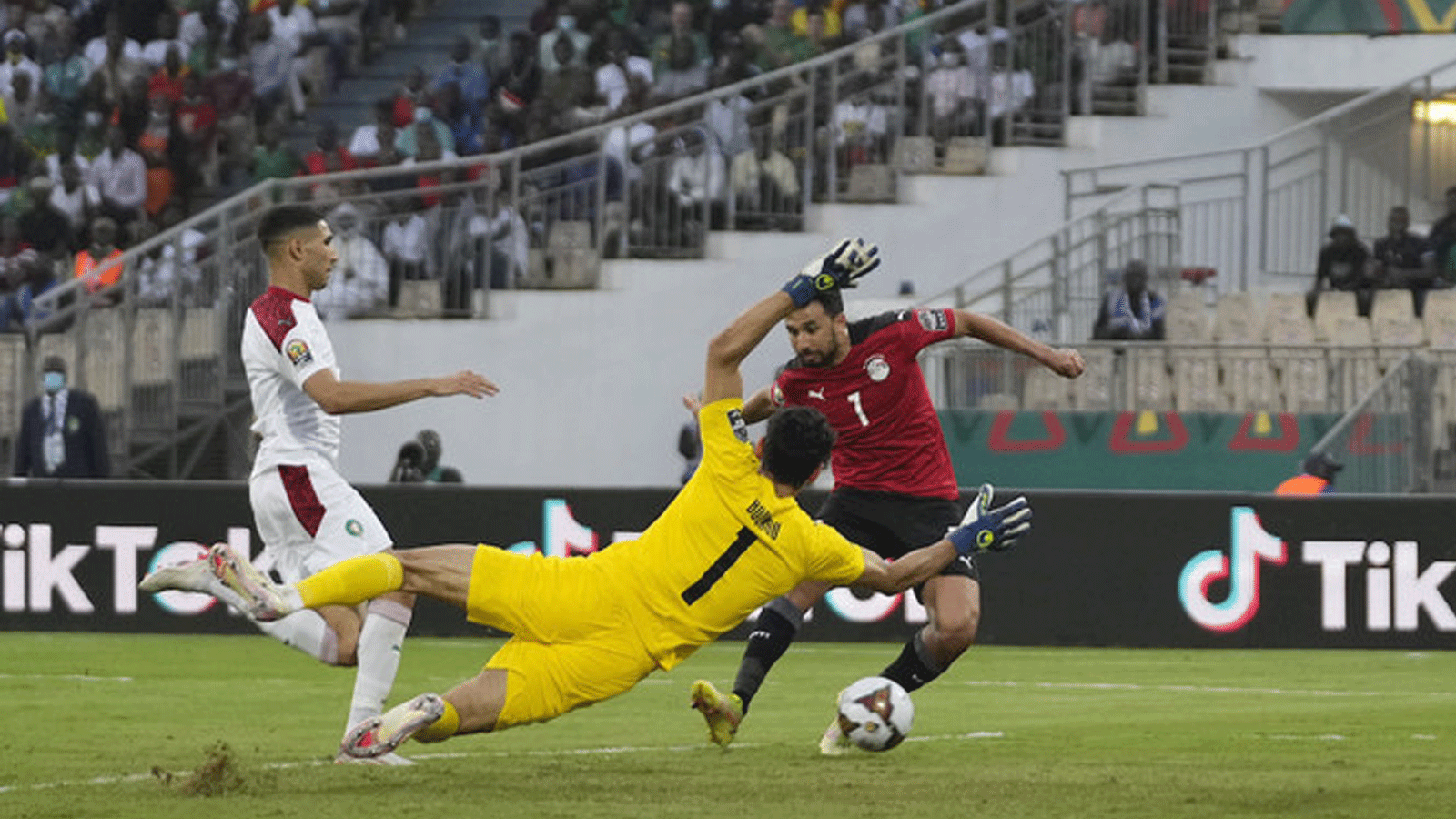 المصري محمود حسن تريزيجيه، إلى اليمين، سجل هدفا في مرمى حارس مرمى المغرب ياسين بونو، في المقدمة. خلال مباراة ربع نهائي كأس آسيا 2022 لكرة القدم بين مصر والمغرب في 30 يناير / كانون الثاني 2022.