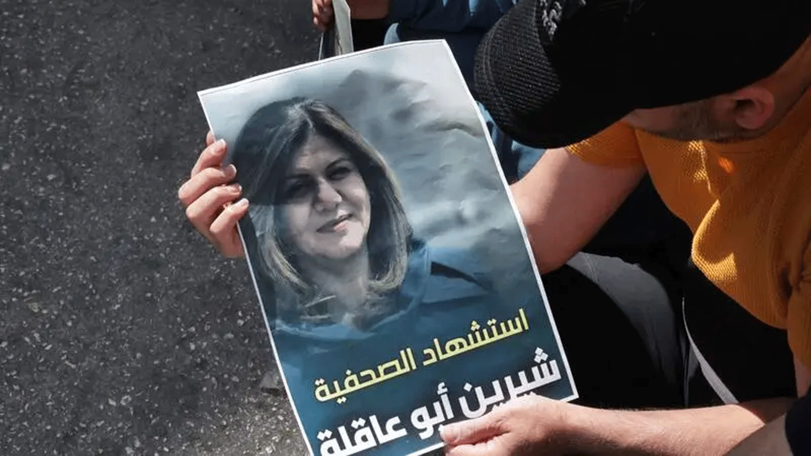 فلسطينيون يحملون ملصقًا يعرض صحفية الجزيرة المخضرمة شيرين أبو عقله، التي قُتلت، برصاص القوات الإسرائيلية أثناء قيامها بتغطية غارة على مخيم جنين للاجئين في الضفة الغربية في 11 أيار\ مايو 2022