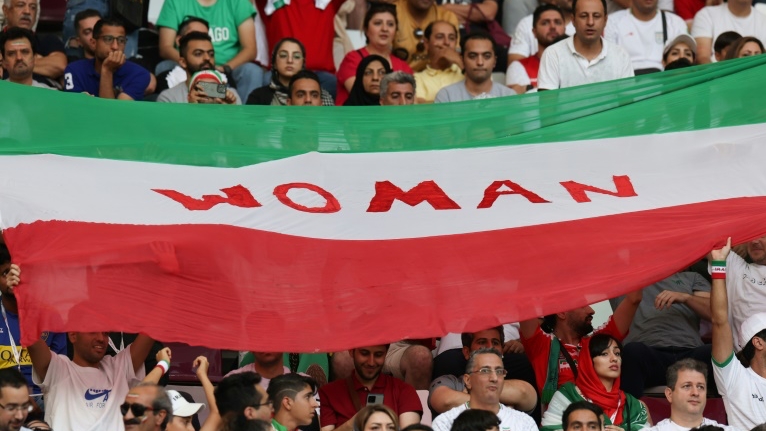 مشجعون لإيران يحملون علم الجمهورية الإسلامية وكتب عليه 