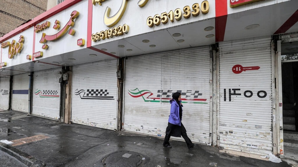 امرأة تسير أمام المحلات التجارية المغلقة على طول شارع ساتارخان في العاصمة الإيرانية طهران في 5 ديسمبر 2022