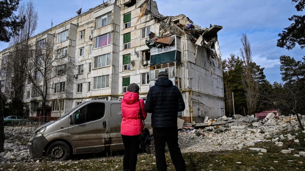 سكان محليون في قرية كلوهينو-باشكيريفكا في منطقة خاركيف ينظرون إلى مبنى سكني دمّرته ضربات في 2 ديسمبر 2022