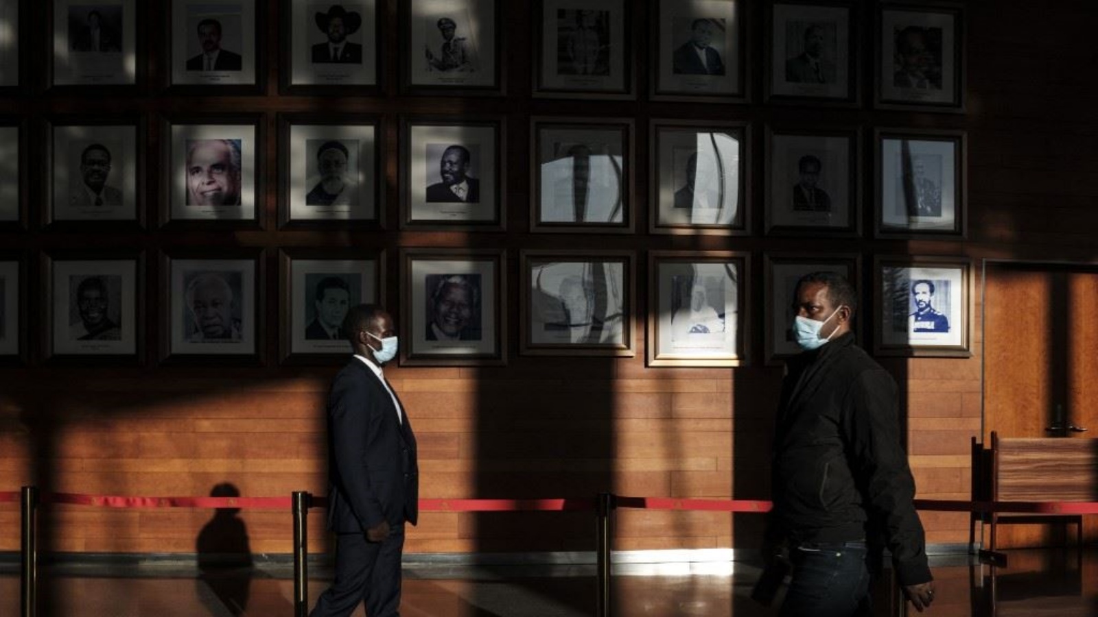 أشخاص يمرون قرب جدار علقت عليه صور رؤساء سابقين للاتحاد الأفريقي قبل افتتاح الدورة العادية الـ36 لمؤتمر الاتحاد الأفريقي في مقره في أديس أبابا 18 فبراير 2023