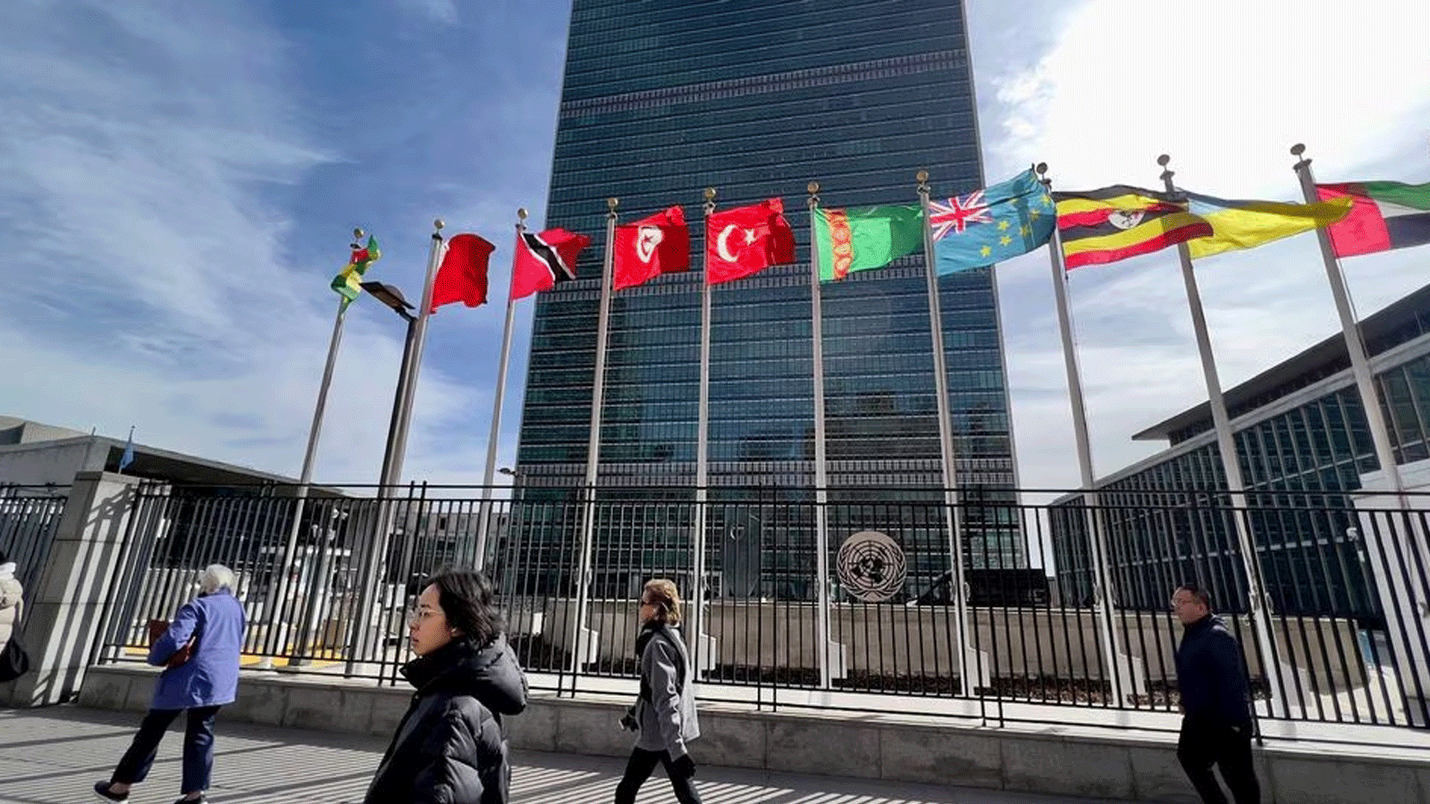 أشخاص يسيرون أمام مقر الأمم المتحدة في نيويورك
