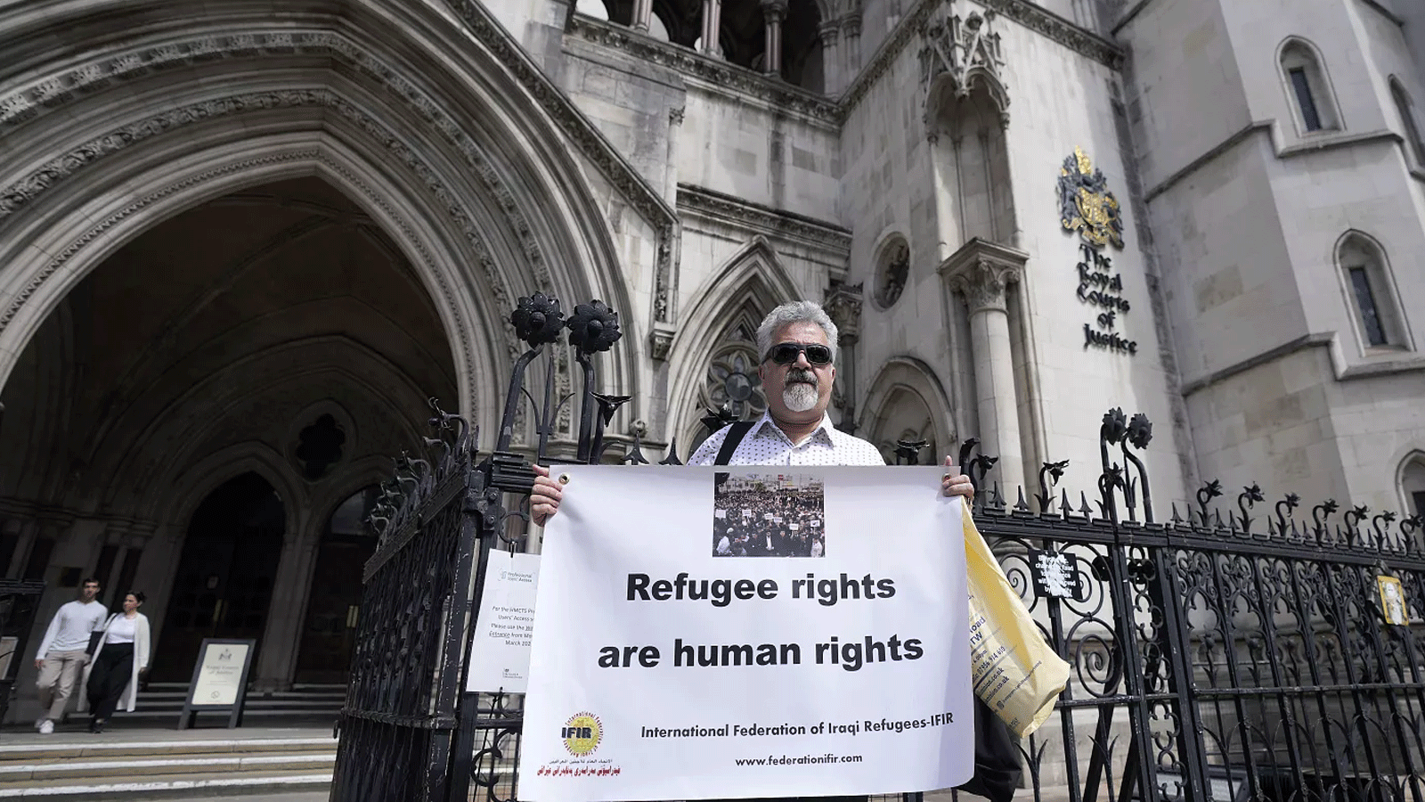 معارض يحمل لافتة دفاعًا عن حقو اللاجئين أمام محمكة الاستئناف البريطانية اليوم الخميس 29 حزيران\ يونيو 2023