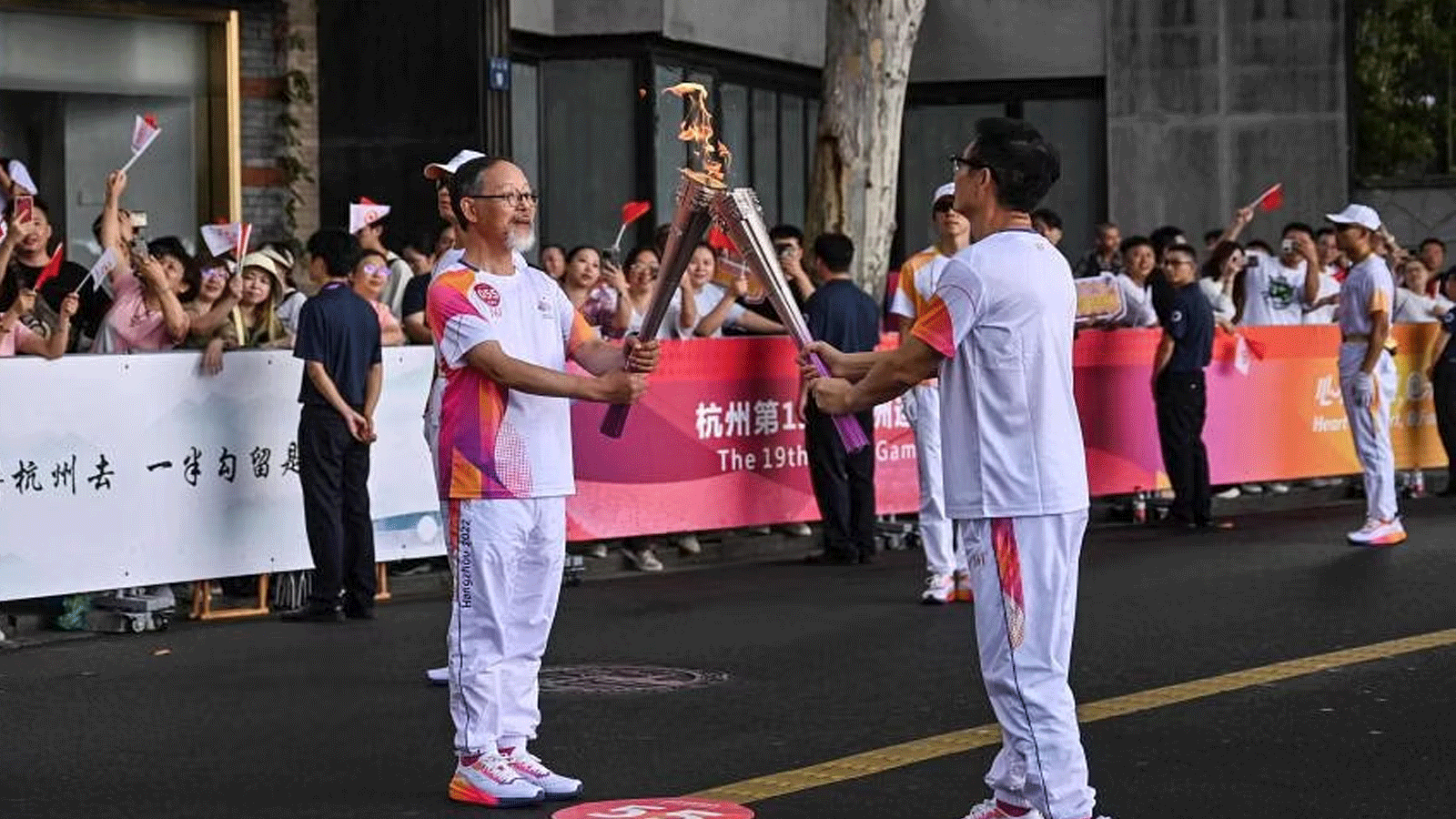 عالم الآثار شو تيانجينغ (يسار) والكاتبة ماي جيا يتبادلان الشعلة خلال تتابع شعلة الألعاب الآسيوية في هانغجو