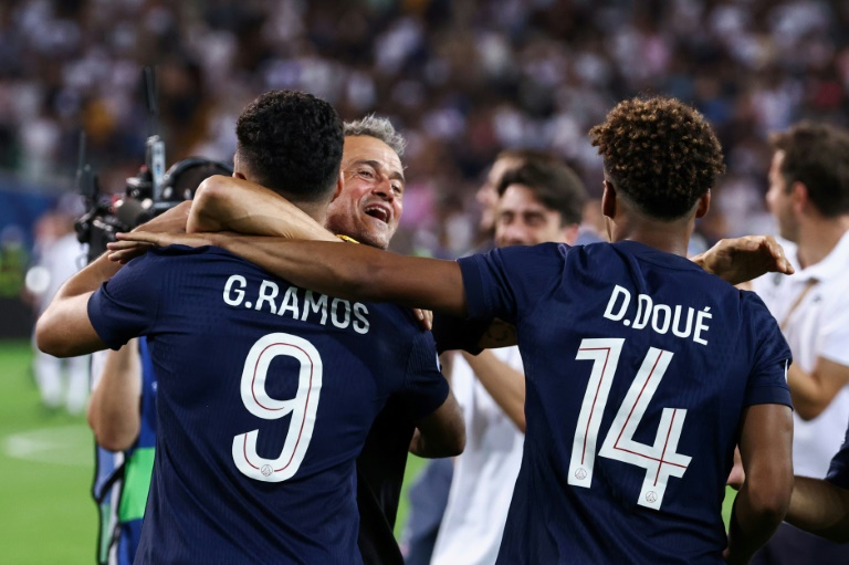 لاعبا باريس سان جرمان البرتغالي غونسالو راموش (يسار) وديزيريه دويه يحتفلان مع مدربهما الاسباني لويس انريكي باحراز لقب الكأس السوبر الاوروبية. 13 اب/اغسطس 2025