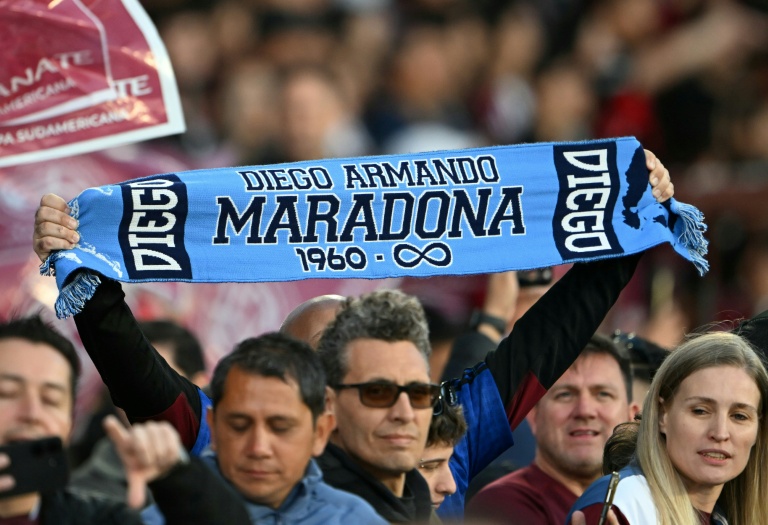 أحد مشجعي لانوس يرفع وشاحا يحمل صورة أسطورة كرة القدم الأرجنتينية دييغو مارادونا في ملعب
