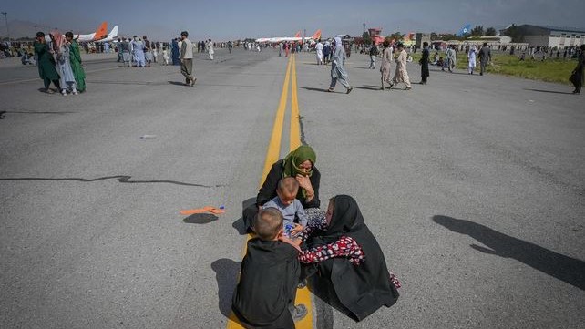 عائلة أفغانية تجلس وسط مدرج مطار كابول منتظرة مغادرة المطار على متن إحدى الطائرات التي أجلت الجنود الأميركيين في أغسطس 2021