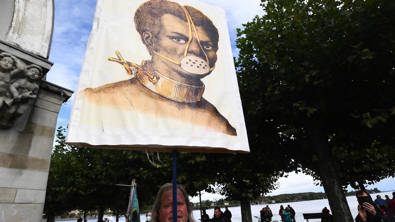 متظاهر ألماني يرفع لافتة تعارض وضع الكمامة