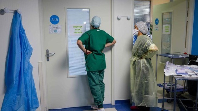 ممرضة تتفقد أحد مرضى موفيد 19 من خلف الزجاج في احدى مستشفيات فرنسا