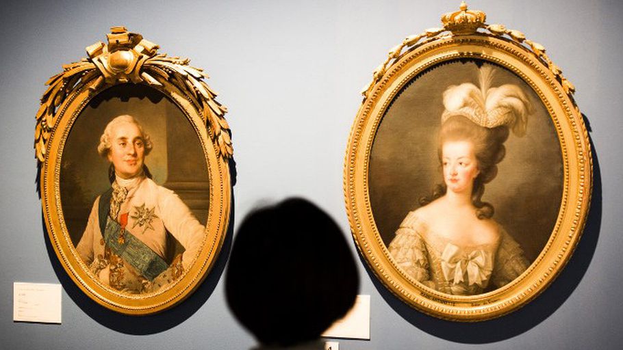 زائرة أمام لوحتين تمثلان الملكة ماري أنطوانيت والملك لويس السادس عشر خلال معرض في طوكيو