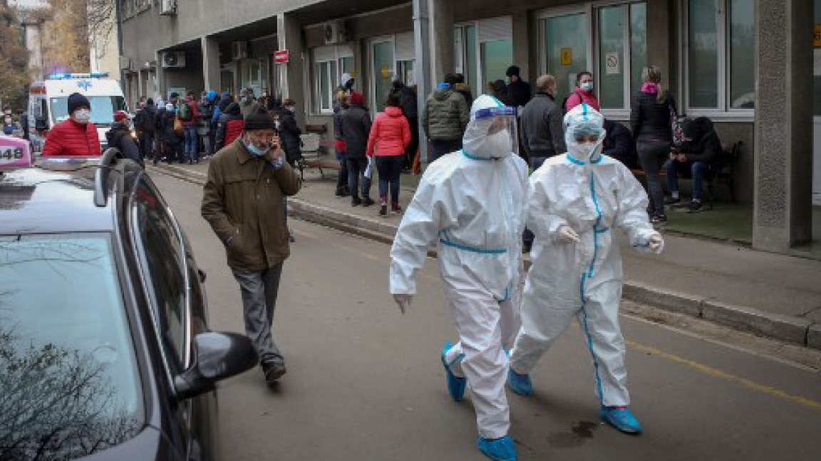 عاملان صحيان بلاسهما الواقي يمران قرب عيادة للأمراض المعدية في بلغراد في 24 نوفمبر الجاري