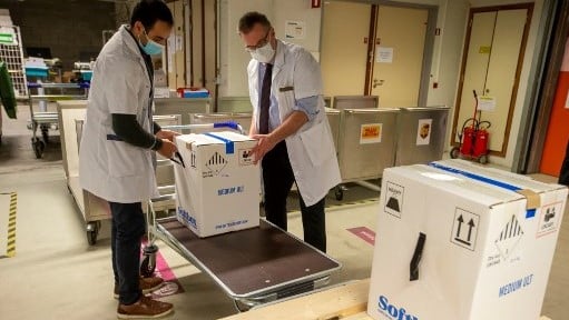 عاملان صحيان يستلمان شحنة من لقاحات بيونتيك في أحد مستشفيات بلجيكا الجمعة