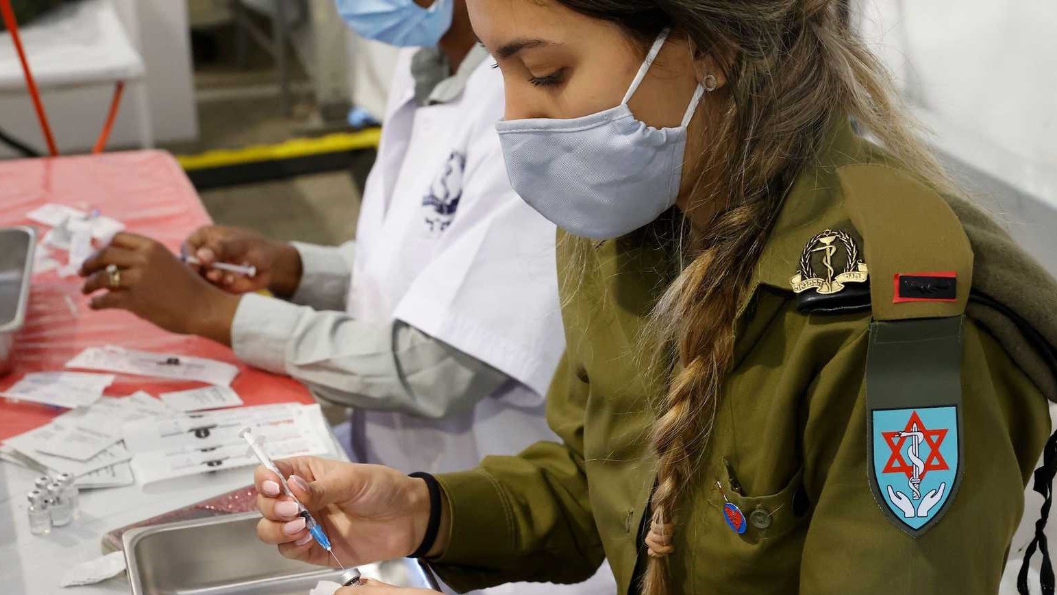 مسعفة في الجيش الاسرائيلي تهيء اللقاح لأحد المرضى