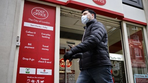 بريطاني بالكمامة الواقية يمر بمكتب للبريد في لندن في 29 ديسمبر