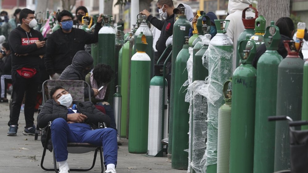 أشخاص يرتدون أقنعة واقية ينتظرون ساعات لإعادة ملء خزانات الأكسجين الخاصة بهم في متجر في كالاو في البيرو