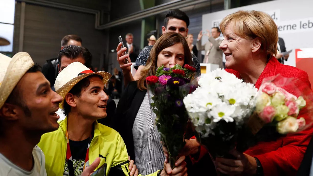 لاجئون سوريون يقدمون الأزهار للمستشارة الألمانية أنغيلا ميركل في شفيرين في شمال ألمانيا في 19 سبتمبر 2017 