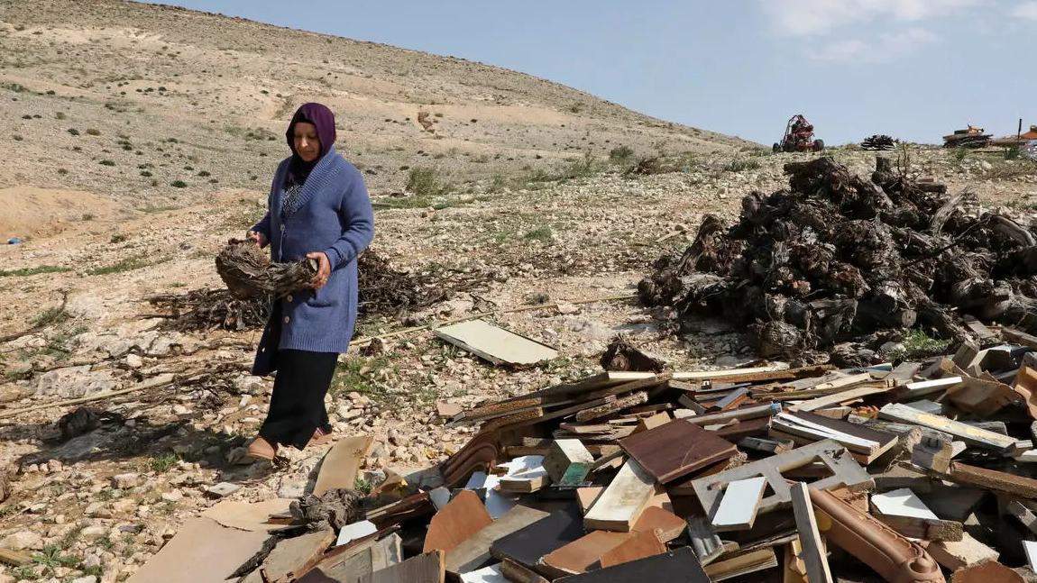 سيدة في قرية تل عراد تمر من أمام منزل هدمته القوات الاسرائيلية