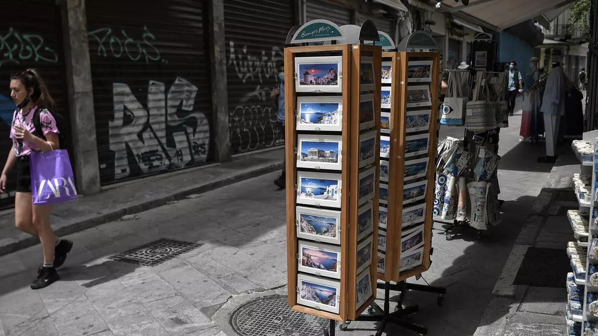 امرأة تمر قرب متجر يبيع سلع تذكارية في وسط أثينا