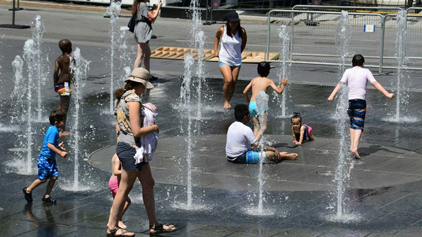 نساء وأطفال يلعبون في نوافير المياه هرباً من الحرّ في ساحة الفنون بمونتريال/ كندا يوم الثلاثاء 3 تموز/ يوليو 2018