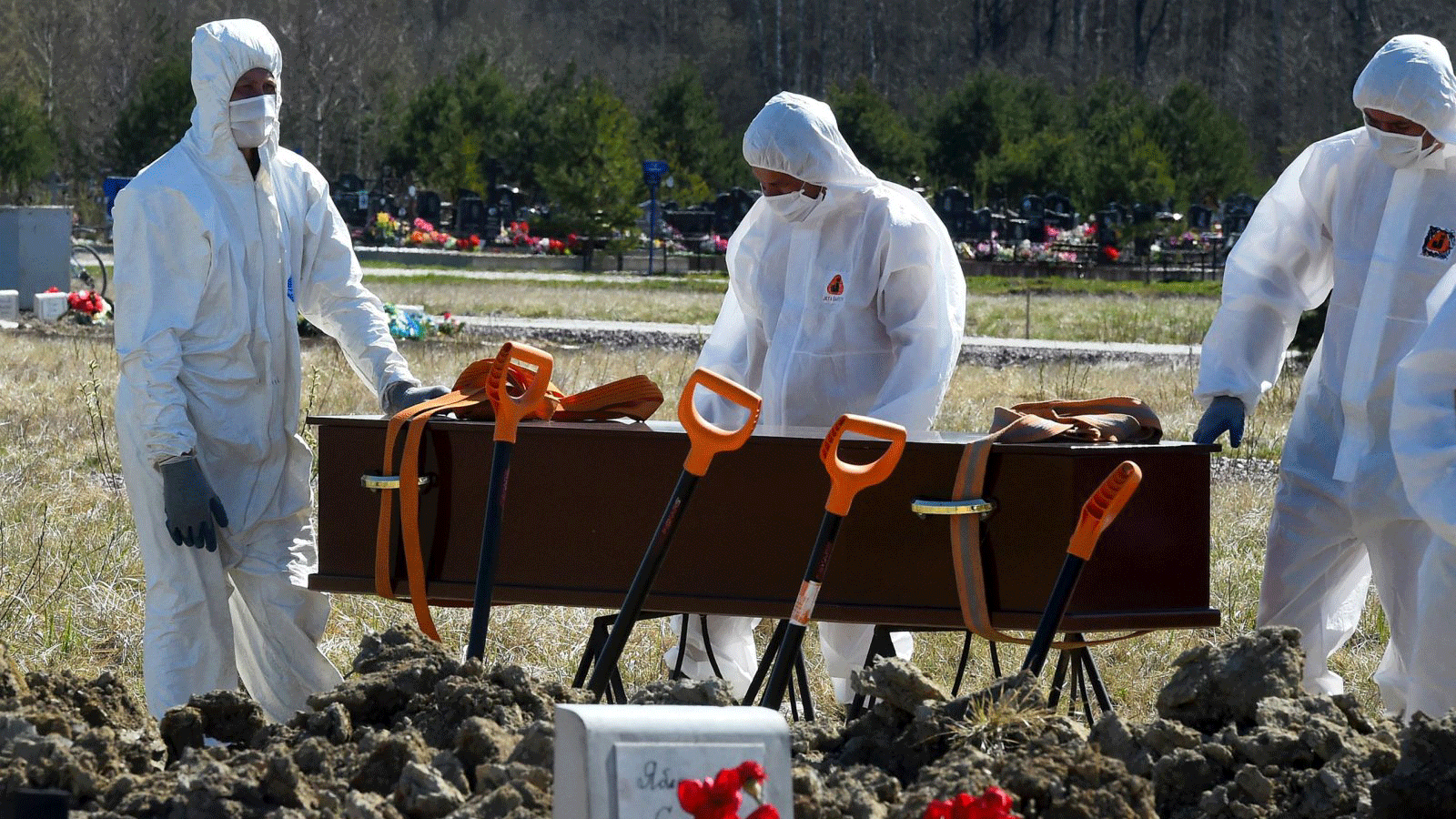 عمال مقبرة يرتدون معدات واقية أثناء دفن ضحية فيروس كورونا في إحدى مقابر ضواحي سانت بطرسبرغ، روسيا، 6 أيار/ مايو، 2020