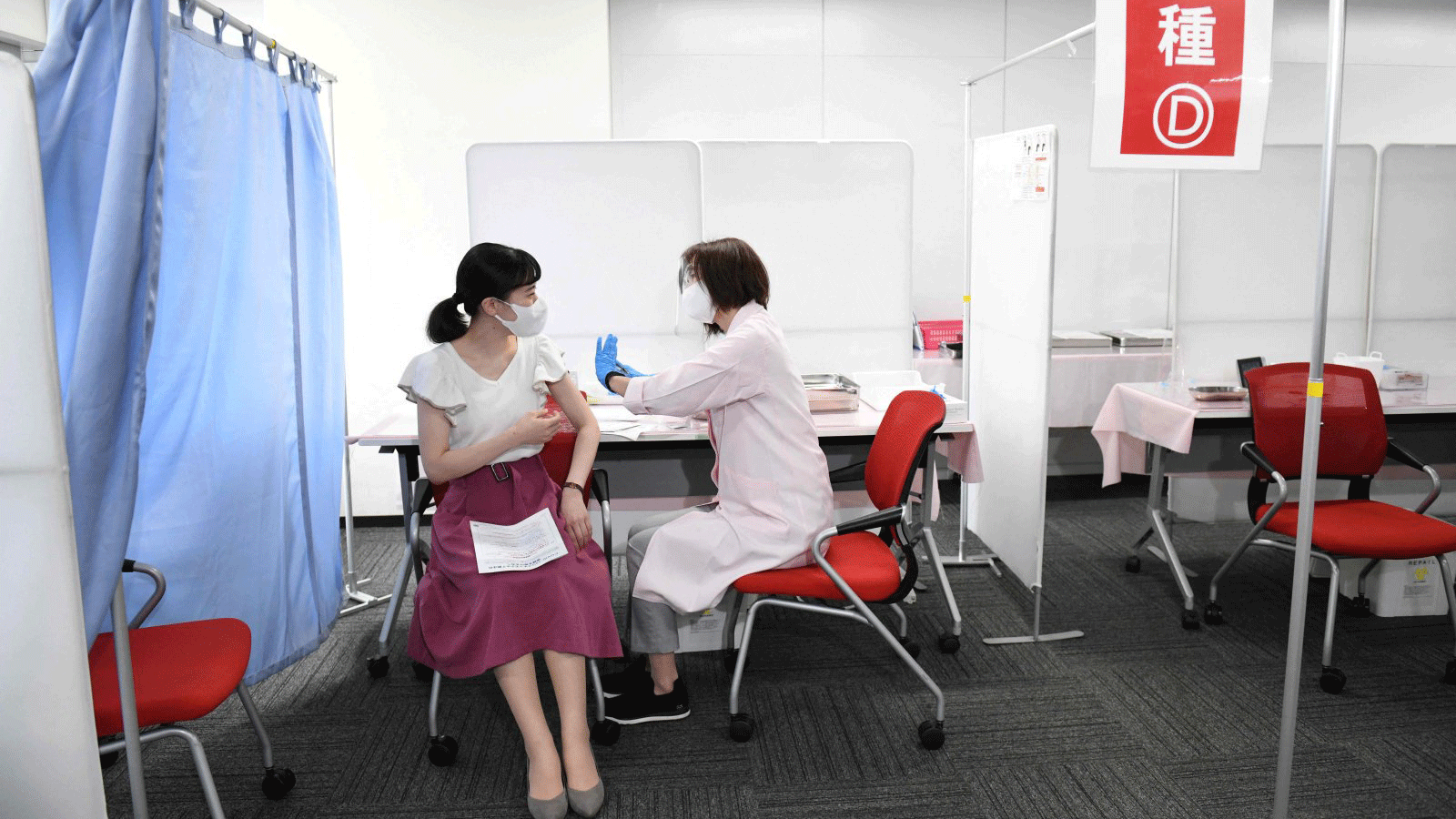 إحدى العاملات في الخطوط الجوية اليابانية تتلقى لقاح موديرنا في اليوم الأول من حملة تطعيم نفذتها الناقلة في مطار هانيدا في طوكيو، اليابان، في 14 حزيران/يونيو 2021