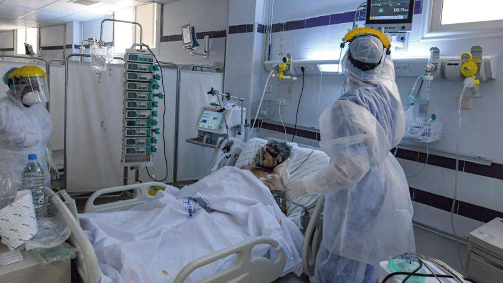 الممرضات يرتدون معدات الوقاية الشخصية (PPE) ويعتنون بمريض كوفيد ذ9 في وحدة العناية المركزة (ICU) في مستشفى في مدينة قابس في جنوب غرب تونس