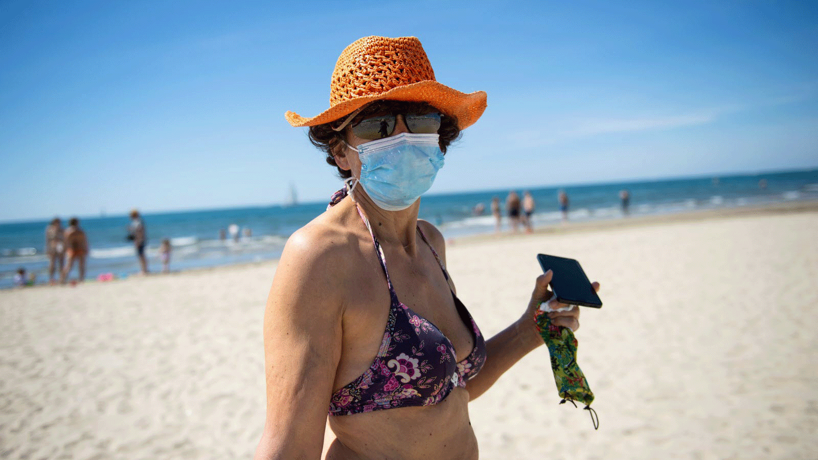 امرأة بلباس البحر ترتدي كمامة على شاطئ فرنسي