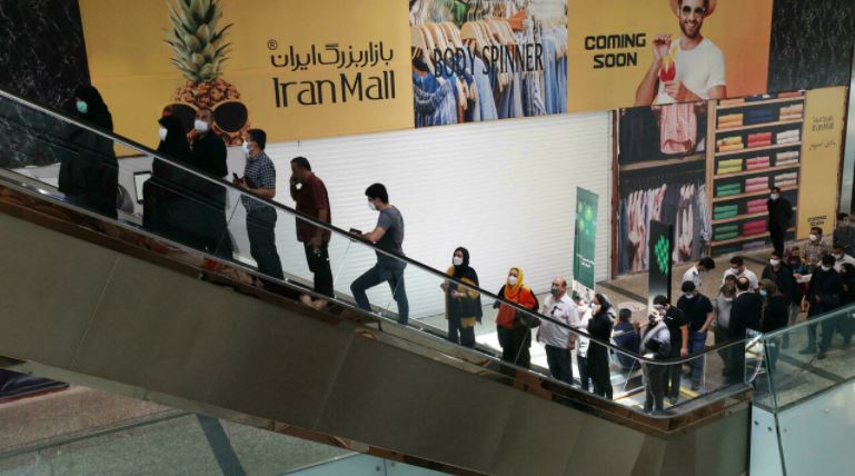 إيرانيون على سلم كهربائي في مركز تسوق في طهران حيث يصطفون لتلقي اللقاح ضد كورونا في مركز للتلقيح