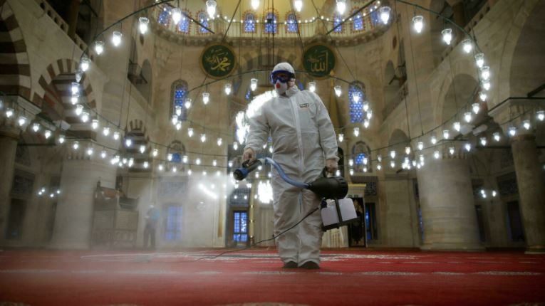 عاملان صحيان يعقمان مسجد كيليك علي باشا في اسطنبول في 11 مارس 2021 