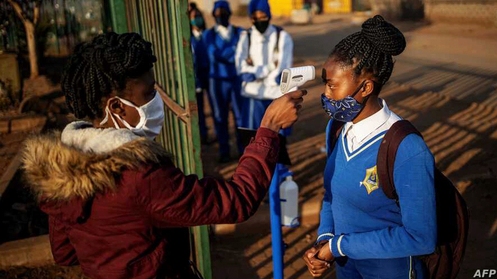 طالبة في مدرسة ويني مانديلا الثانوية تم قياس درجة حرارتها عند دخولها مبنى المدرسة قبل استئناف الدراسة في بلدة تمبيسا، إكورهوليني، جنوب إفريقيا. في 8 حزيران/ يونيو 2020