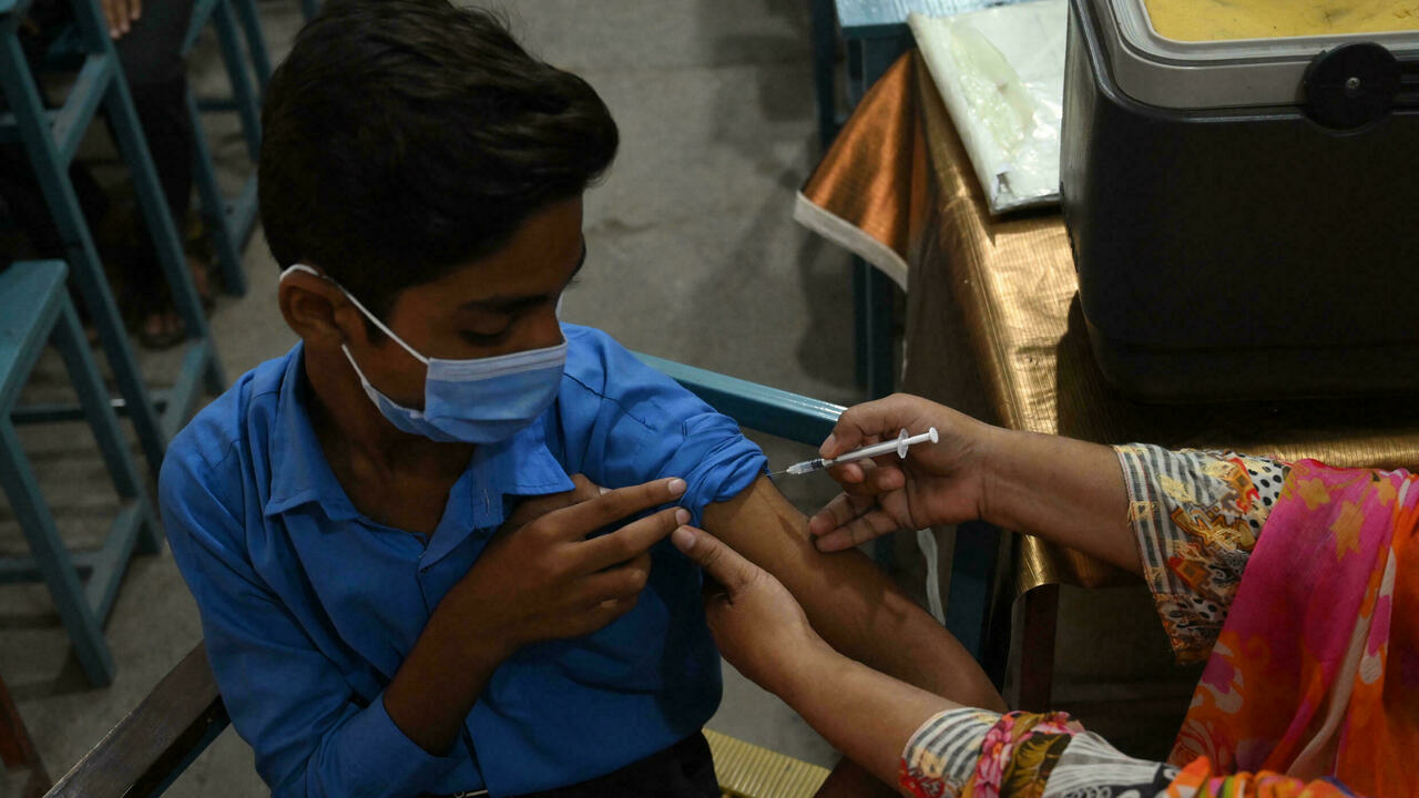 عاملة في مجال الصحة تعطي لقاح فايزر لتلميذ في مدرسة في لاهور في باكستان في 30 أيلول/سبتمبر 2021