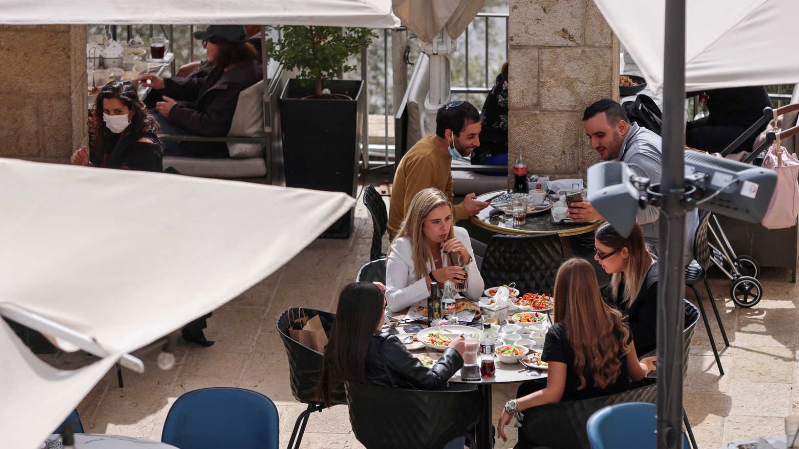 شباب إسرائيليون في مطعم في تل أبيب، بعدما حصلوا على التصريح الأخضر بتلقّيهم جرعة معزّزة من لقاح كورونا. (أرشيفية)