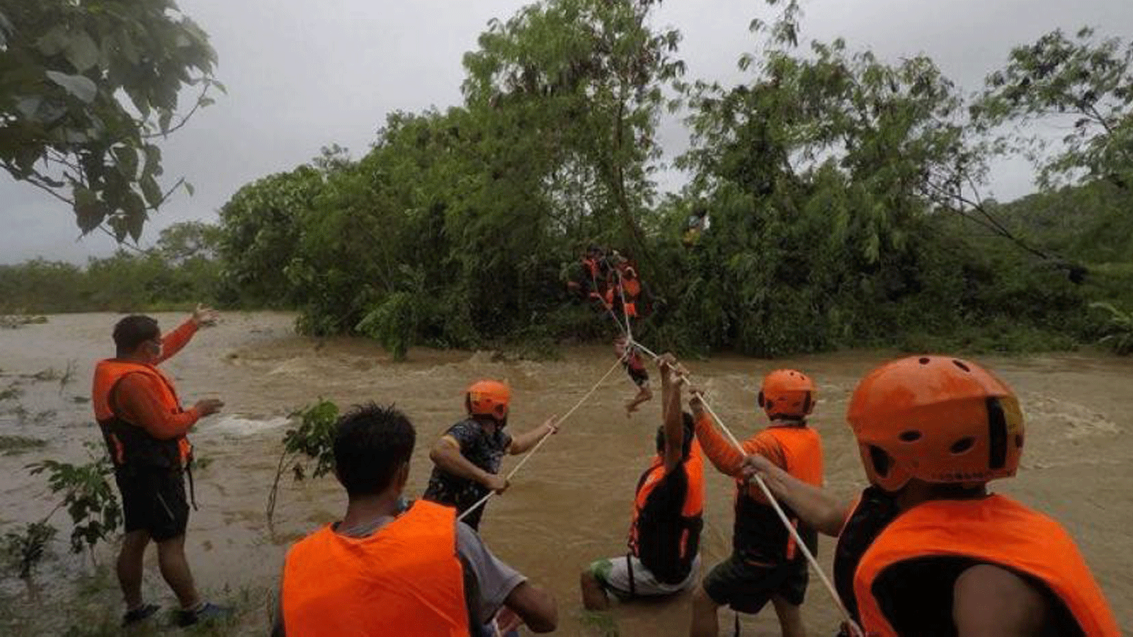 عمال الإنقاذ يقومون بإجلاء السكان من منازلهم بالقرب من نهر متضخم بسبب الأمطار الغزيرة التي سببتها العاصفة الاستوائية كومباسو في مقاطعة كاجايان شمال مانيلا.