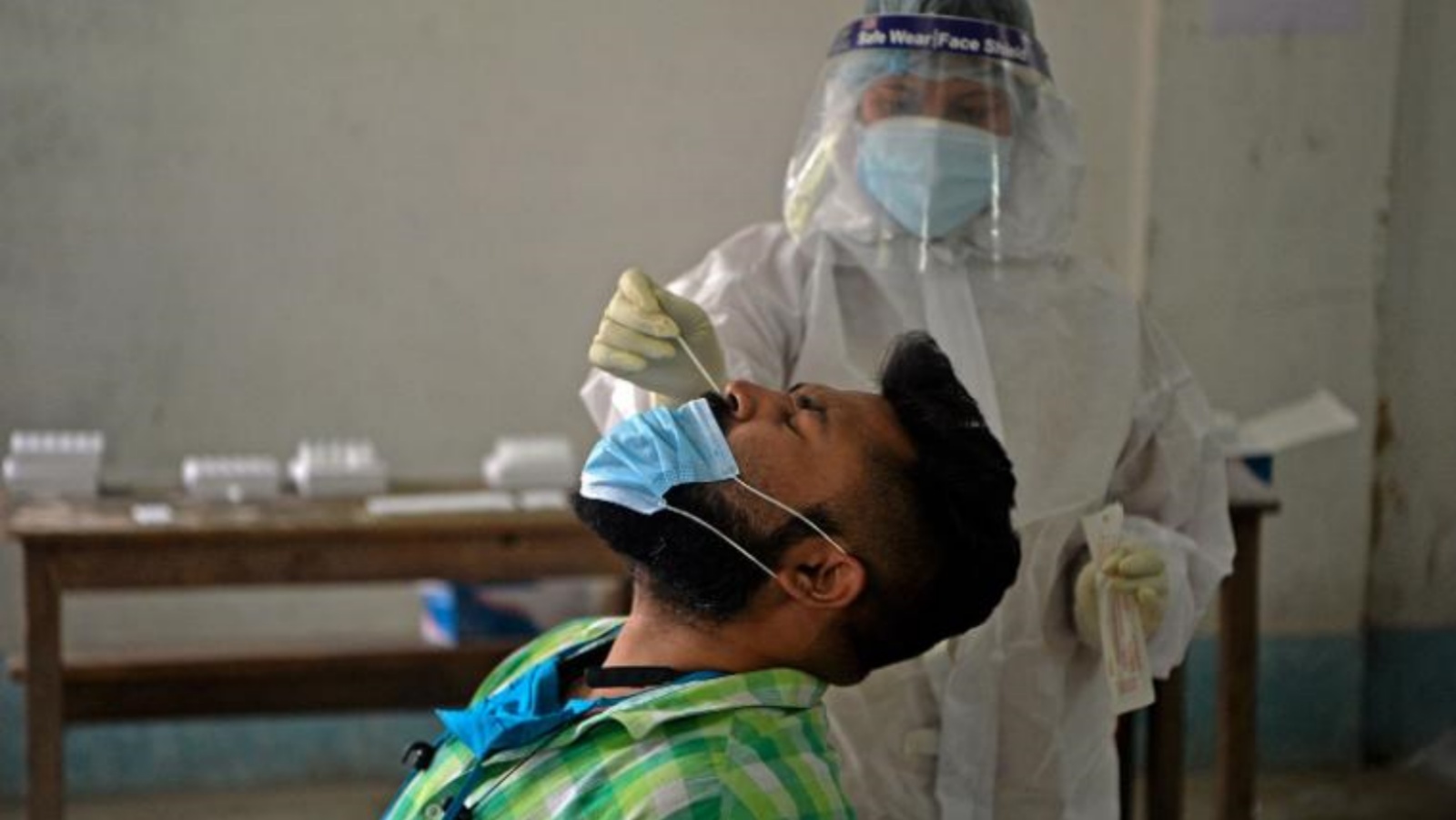 عاملة صحية تأخذ عينة فحص كورونا لمريض في مركز للرعاية الصحية في سيليغوري، الهند.