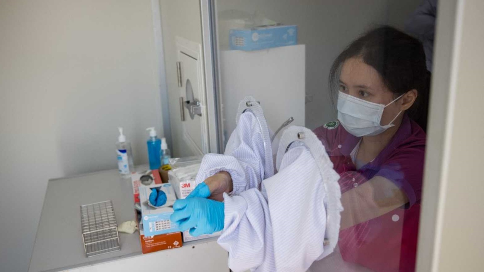 عاملة صحية تتخلص من القفازات الملوثة في غرفة مخصصة للعزل في إحدى المستشفيات. (أرشيفية)