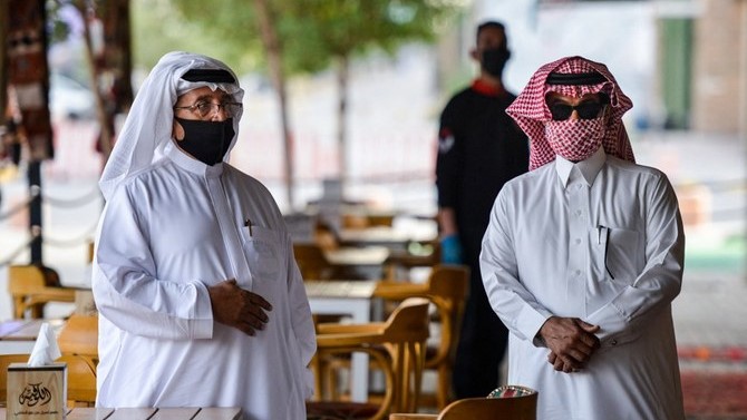 سعوديان مكممان ينتظران فراغ طاولة في أحد مطاعم الرياض في 21 يونيو 2021